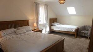 Un dormitorio con dos camas, una ventana con cortinas, una lámpara y un aplique de techo.