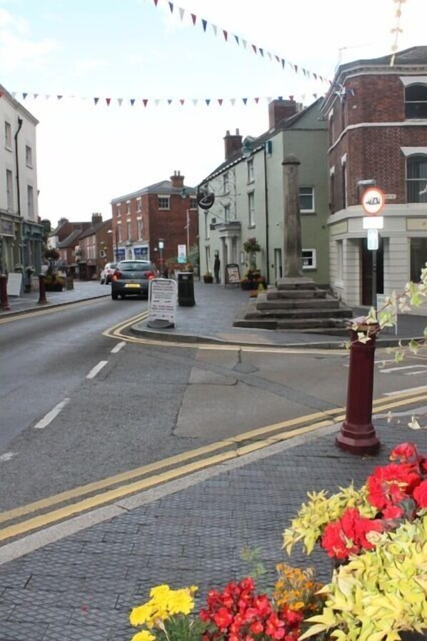 A street view with buildings, a car, and a pedestrian crossing. -   Hidden Cottage for Two in Cheadle Staffordshire, ideal for the  Peak District. (Cheadle)