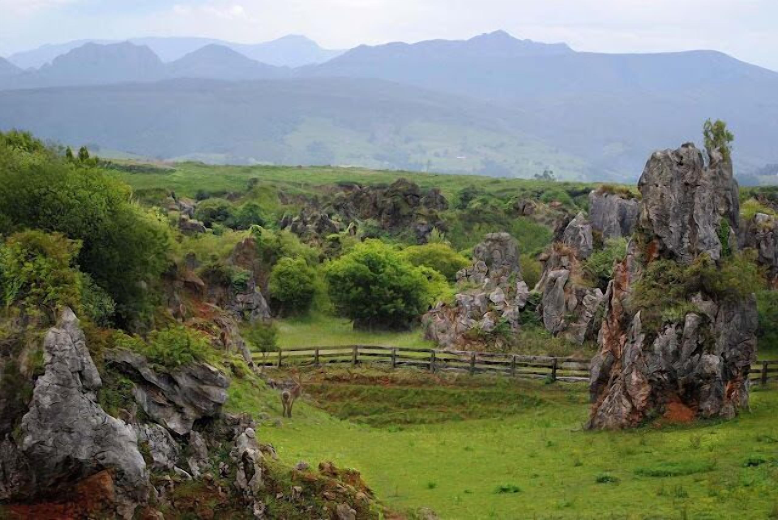 Eine gebirgige Landschaft mit Felsformationen und einem Holzzaun.