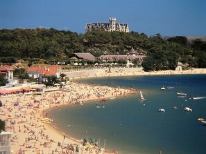 Ein Strand mit einem schlösserartigen Gebäude im Hintergrund.