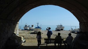 An arched stone structure overlooking a beach with several boats. - Amazing panoramic terrace in Castel di Tusa - air conditioning & wi-fi (Tusa (me))