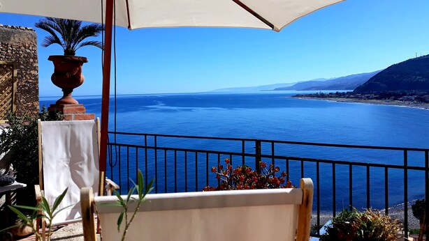 A balcony with a view of the sea, a potted plant, and a white umbrella. - Amazing panoramic terrace in Castel di Tusa - air conditioning & wi-fi (Tusa (me))
