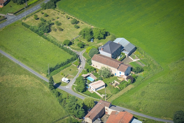 Vista aérea de una propiedad rural con una casa principal, un edificio más pequeño adosado y una piscina.