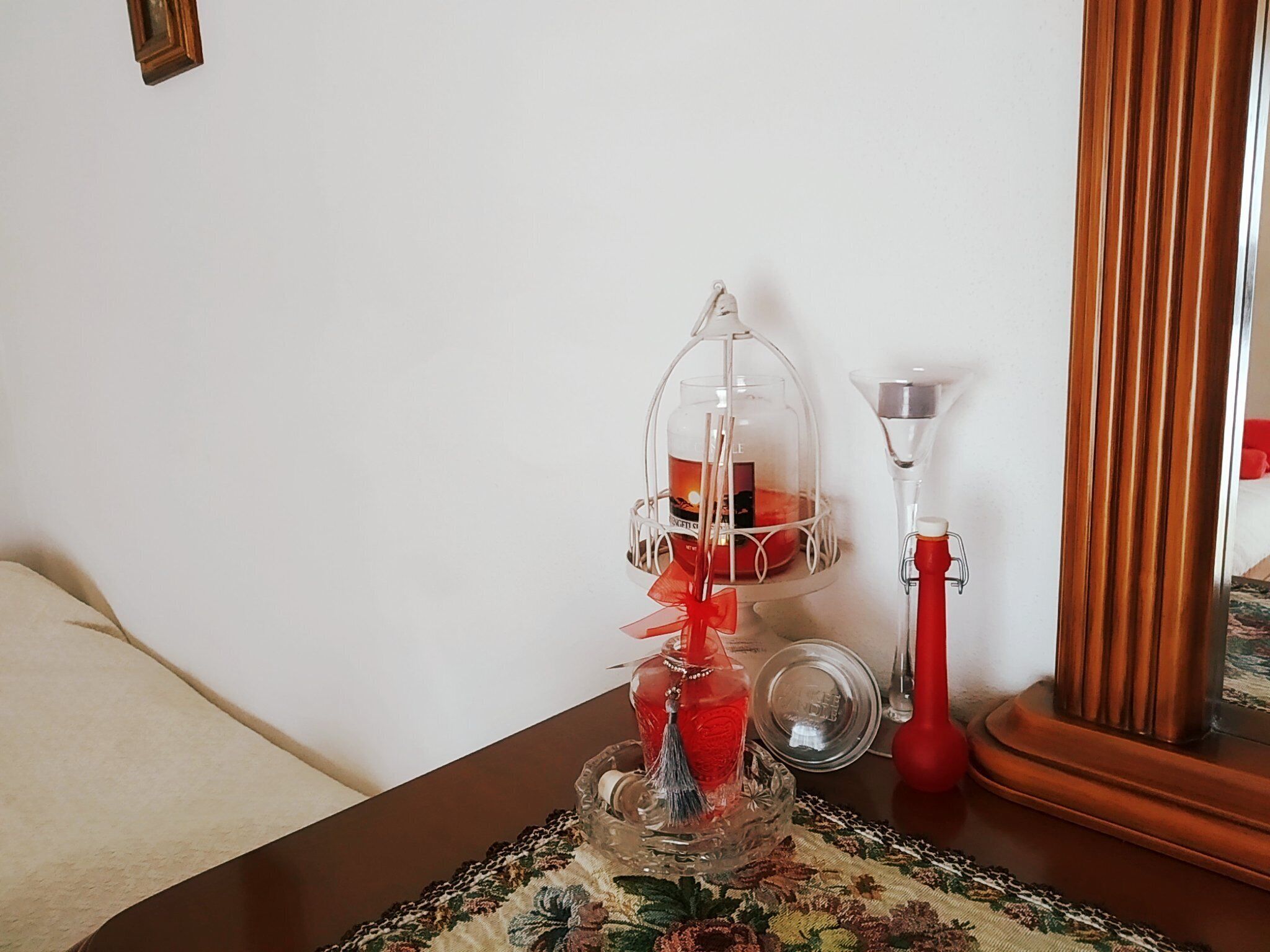 Ein Zimmer mit einem Holztisch, einem Kerzenhalter aus Glas und einer roten Vase.