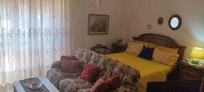 Ein Zimmer mit Bett, einer Schlafcouch, einem Nachttisch und einer Lampe.
