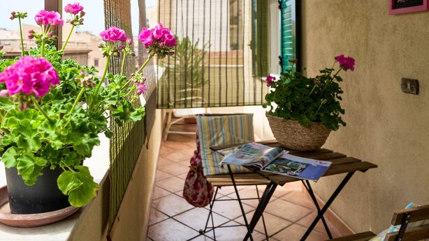 A balcony with potted geraniums, a wicker basket, a magazine on a small table, and a 'Bienvenue' sign on the wall. - Penthouse Finocchiaro - Terrace in the Center Wifi Free (PALERMO)