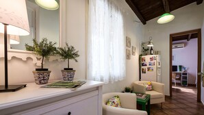A well-lit room with a white dresser, two potted plants, a sofa, and a table. - Penthouse Finocchiaro - Terrace in the Center Wifi Free (PALERMO)