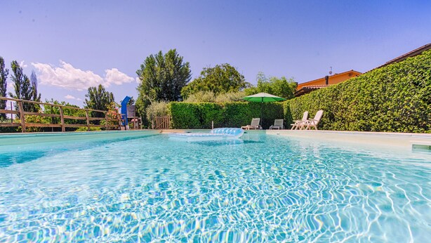 A clear swimming pool with lounge chairs and a hedge. - One Bedroom Apartment   for 2/4 people (Gemini) (assisi)