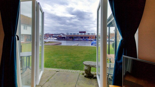 Una habitación con un gran ventanal corredizo que da a un área exterior con césped y vistas al agua y a barcos.