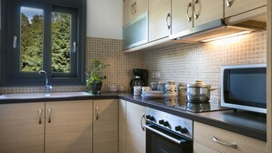 Una cocina moderna con armarios de madera, estufa de acero inoxidable, microondas y ventana con vista a árboles.