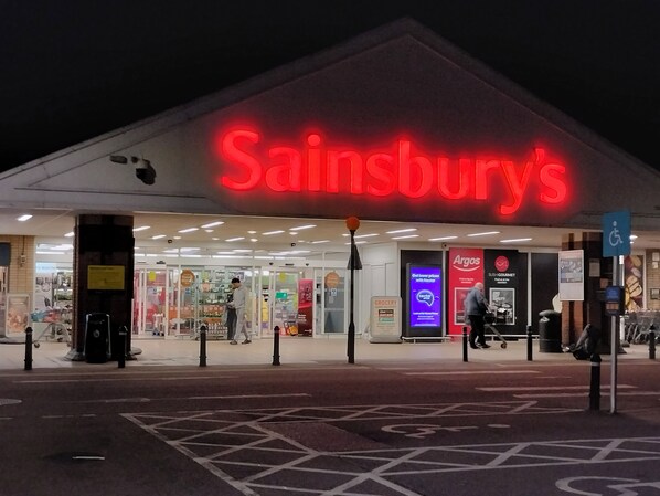 A Sainsbury's store with a prominent red sign, a visible entrance, and a disabled parking sign. - Canalside Chic – Your London Escape Starts Here! WIFI and Airport Transfers (Apsley Hemel Henmpstead)