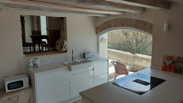 A kitchen with a white countertop, a sink, and a microwave. There is a window with a view of trees and a brick wall. - Luxury cottage, big terrace, marvelous view (Brendola)
