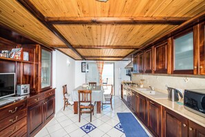 Une cuisine avec des meubles en bois, une table à manger, des chaises et un îlot central doté d’un évier et d’une cuisinière.