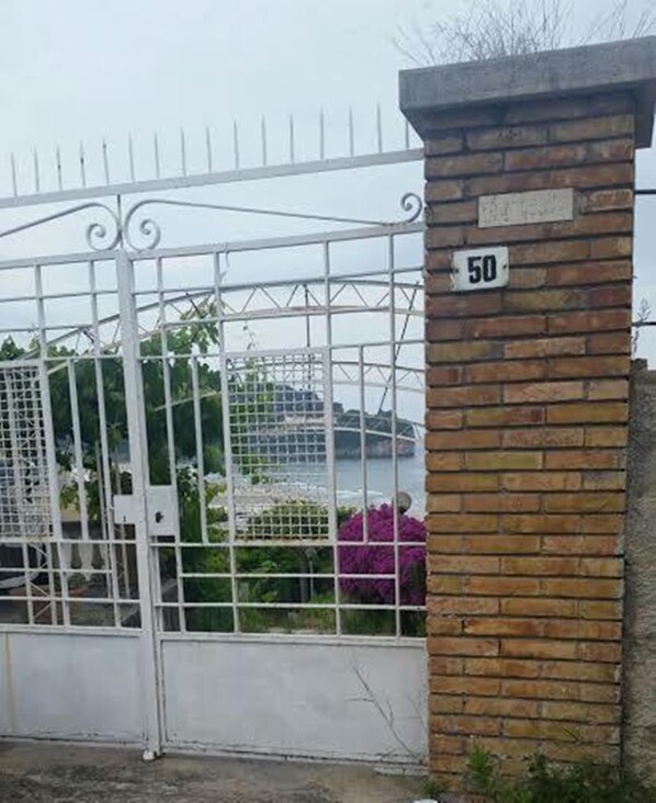 Une entrée fermée par un portail, avec un mur en briques et un portail en métal.