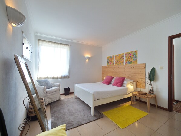 A bedroom with a bed, a chair, a bedside table, a mirror, and a window with curtains. - Superb view! (Madalena (Pico))