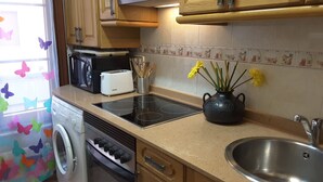 A kitchen with a stove, a toaster, a sink, and a washing machine.