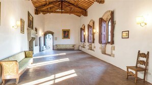 Um corredor amplo com teto de madeira, paredes de pedra e um banco.