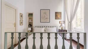 A bedroom with a bed, a nightstand, a lamp, a window with curtains, and a door. - For My Friends B & B - Sun Room (Roma)