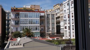 Edifício residencial de vários andares com varandas, antenas parabólicas e um telhado vermelho.