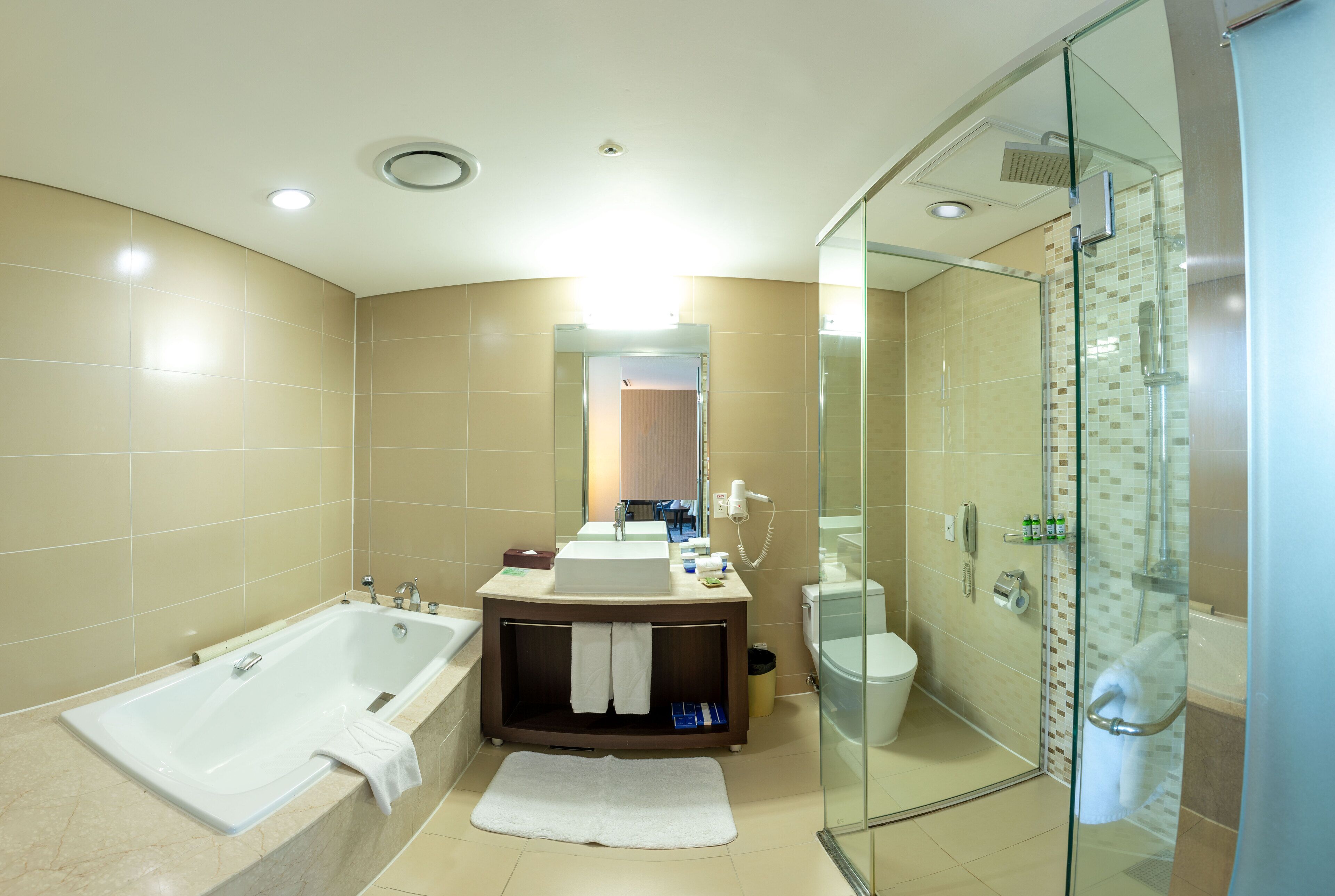 Un baño moderno con bañera, ducha con mampara de vidrio y tocador con lavabo y espejo.