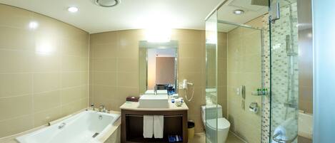Un baño moderno con bañera, ducha con mampara de vidrio y tocador con lavabo y espejo.