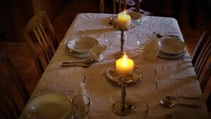 A dining table set for four with a lit candle centerpiece, white tablecloth, and wooden chairs. - VILLA WITH LARGE TERRACES AND GARDENS WITH SEA VIEW (SCIACCA)