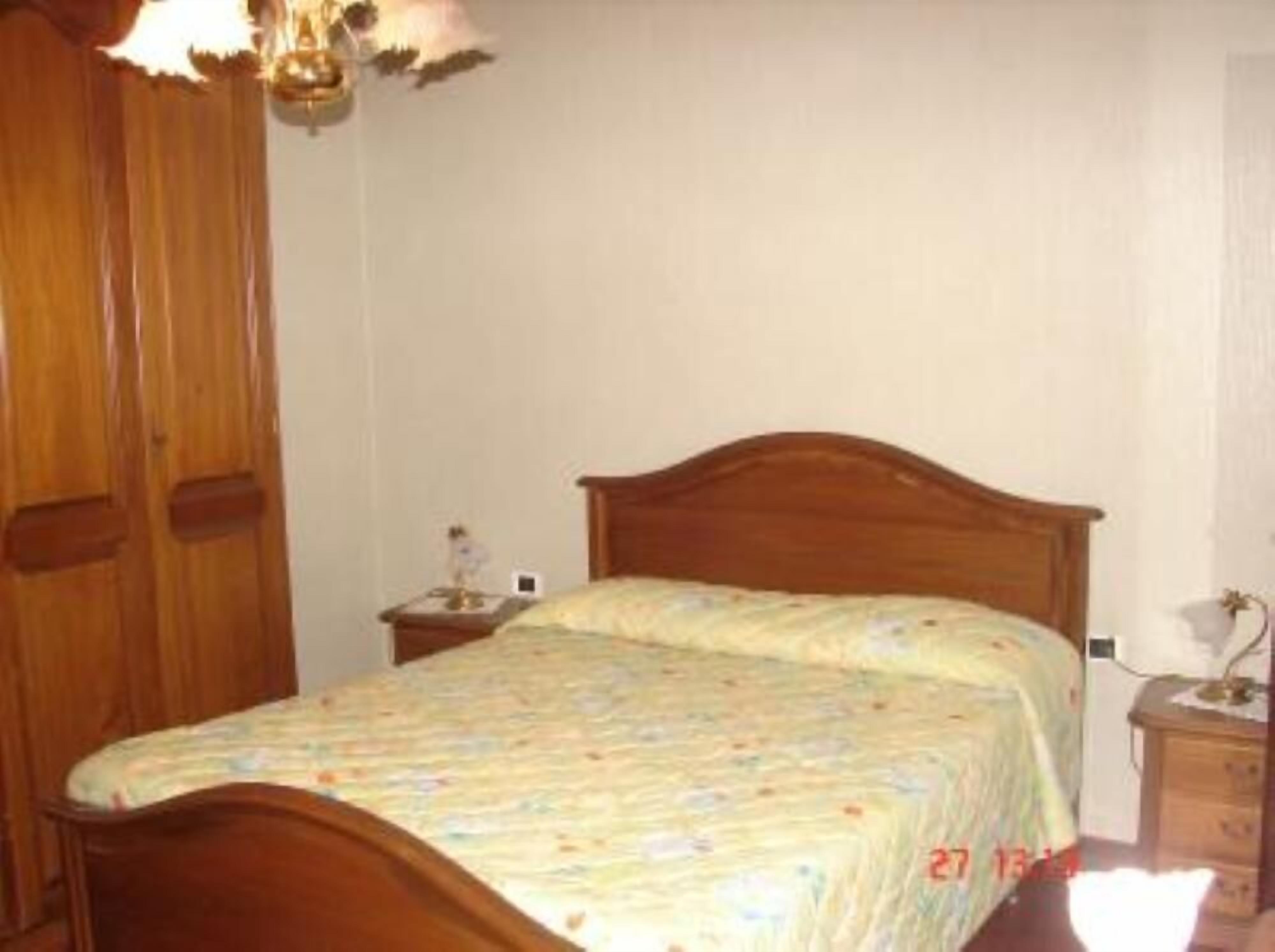 A bedroom with a wooden bed, a nightstand, and a wardrobe.