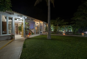 A modern house with large glass doors, a well-maintained lawn, and outdoor lighting.