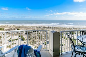 A balcony with a view of the beach and ocean.