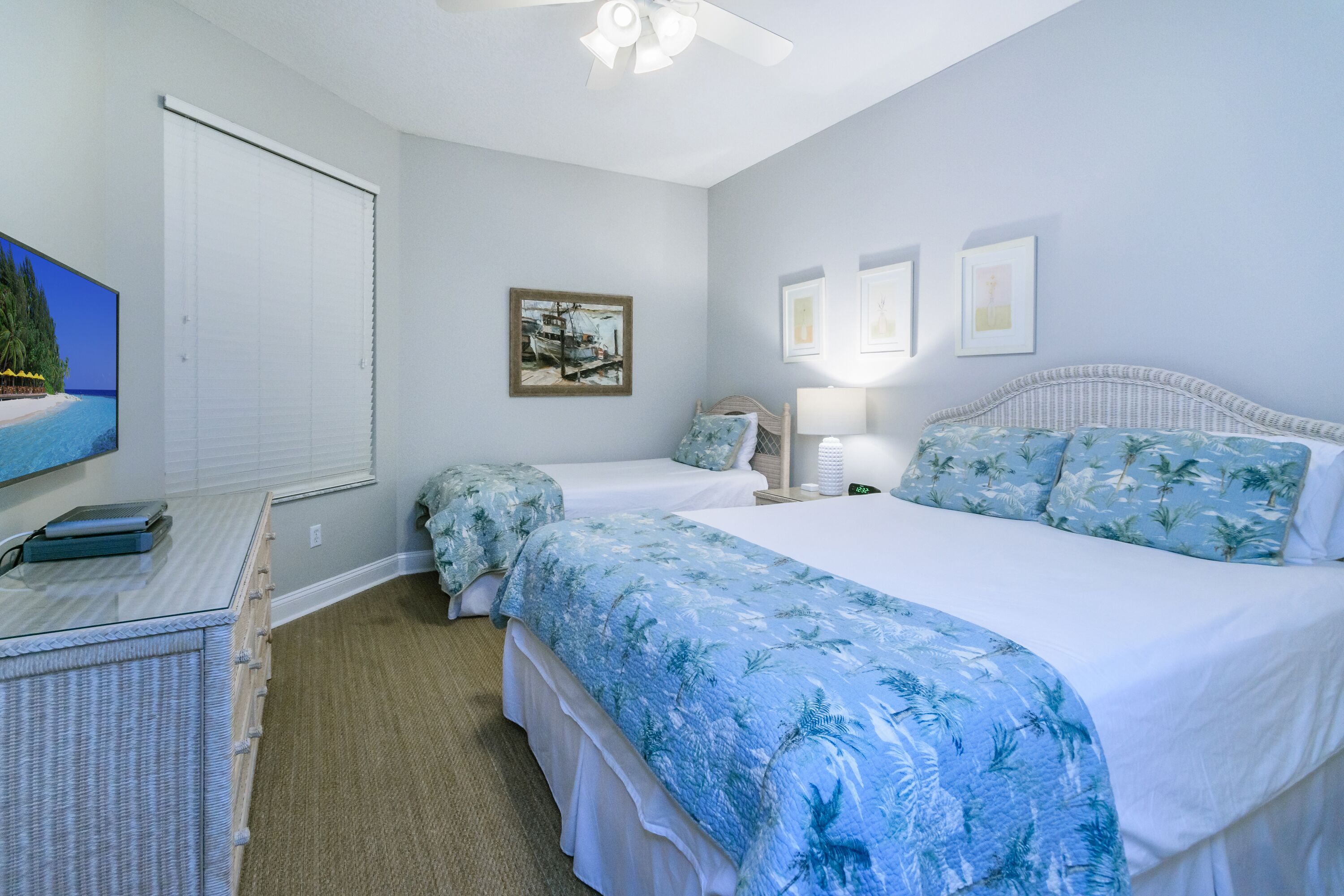 A bedroom with two beds, a TV, and a window with blinds.