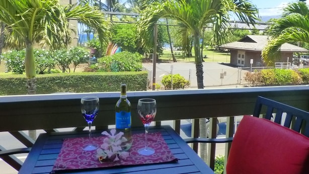 En balkon med et bord dækket til to personer, med en vinflaske og to glas.
