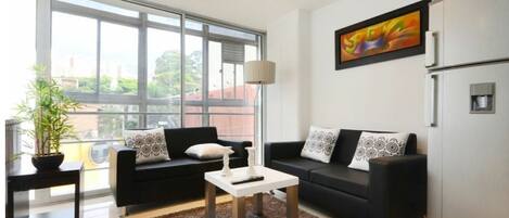 Relax in this urban retreat with a city view, featuring a sofa, coffee table, and potted plant.