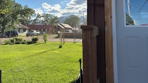 Un edificio de madera con una puerta blanca, una ventana pequeña y un porche.