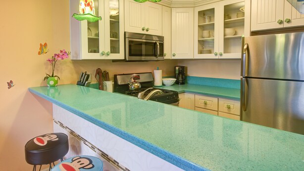 A kitchen with white cabinets, a stainless steel refrigerator, and a teal countertop.