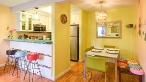 A kitchen with a microwave, refrigerator, and bar stools.