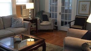 Una sala de estar con sofá, sillones, una mesa de centro y una puerta con paneles de vidrio.
