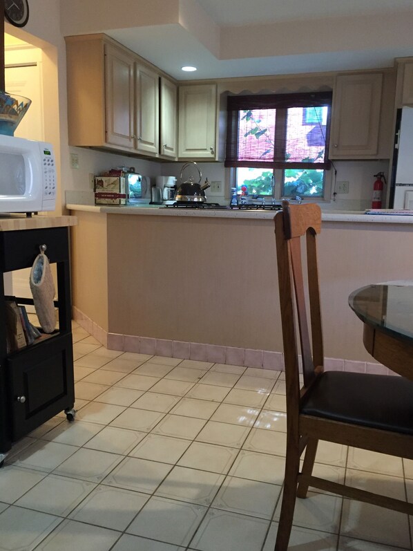 Una cocina con microondas, hervidor y ventana con vista a zonas verdes.
