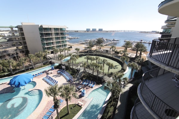 A hotel with a pool area, lounge chairs, and a view of the water and bridge.