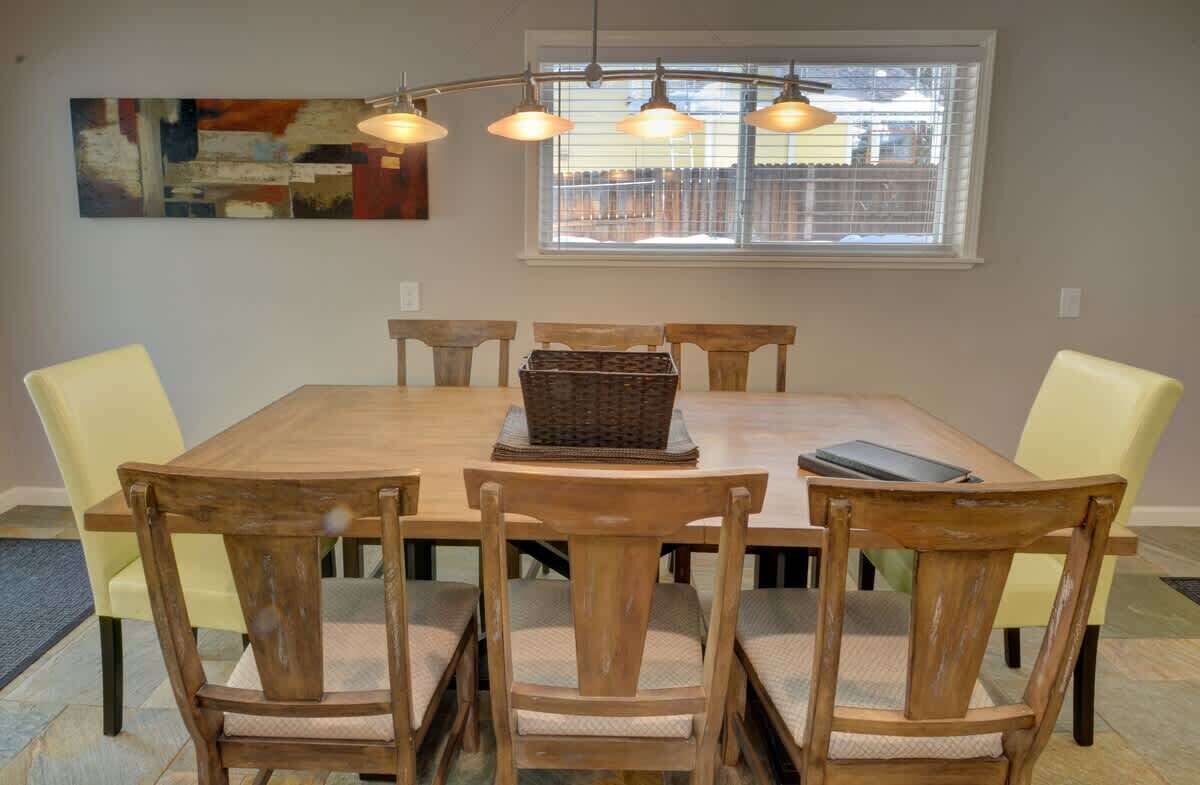 Un comedor con una mesa de madera, seis sillas y una lámpara colgante.