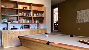 A pool table with a wooden cabinet and shelves above it, containing books and a microwave. - West Hills HideAway, a 3-Bedroom Gem in the Hills of Bend (Bend)