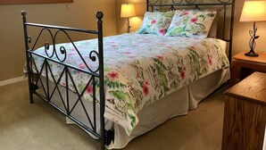 A bed with a floral bedspread, two bedside lamps, and a nightstand with a lamp. - West Hills HideAway, a 3-Bedroom Gem in the Hills of Bend (Bend)