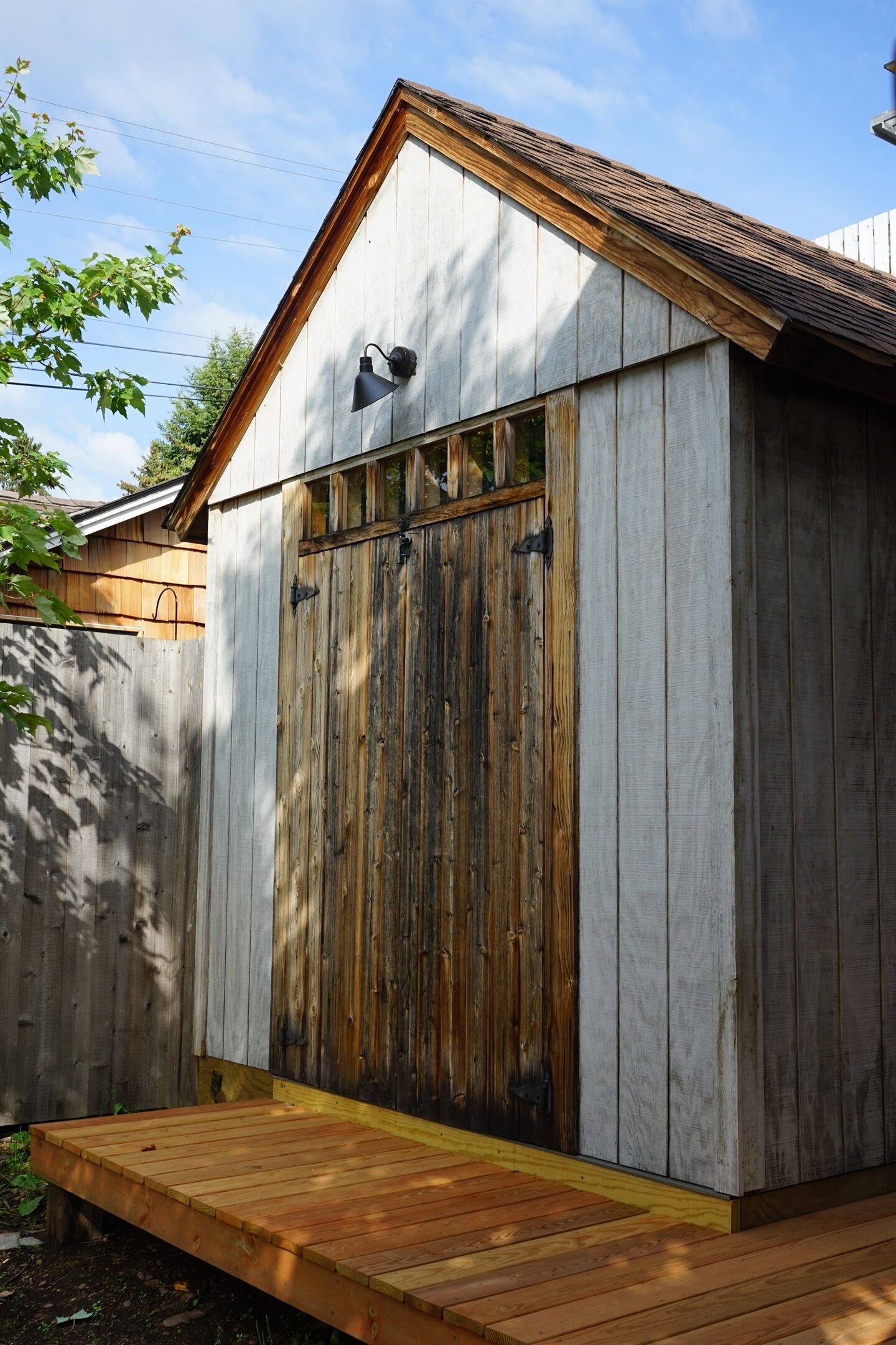 A wooden shed with a slanted roof, a wooden door, and a small wooden platform at the front.
