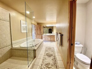 A bathroom with a glass shower enclosure, a bathtub, a toilet, and a sink.