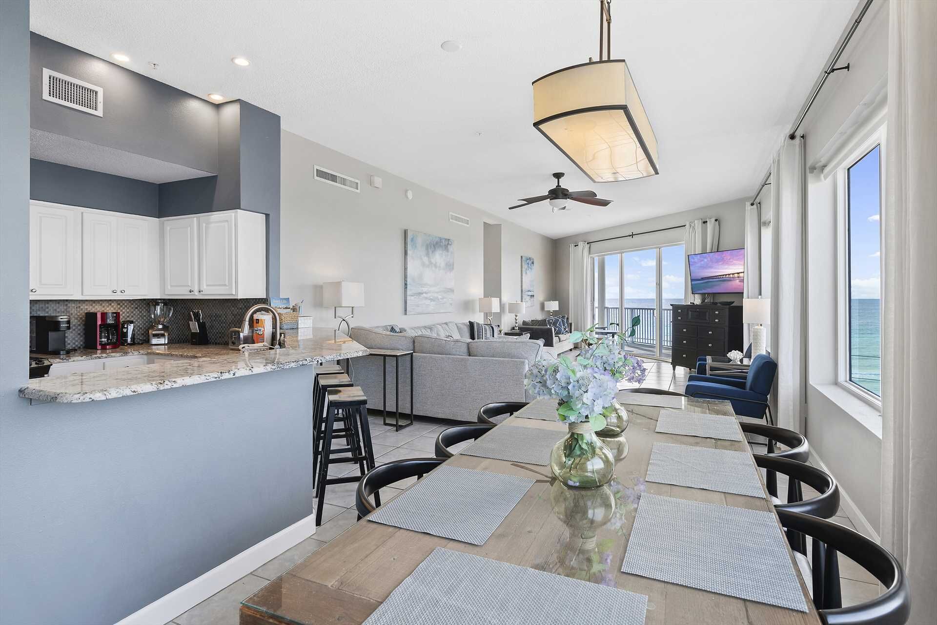 A modern kitchen with white cabinets, a central island, and a dining area with a glass table and chairs.