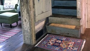 A staircase with wooden steps leading to a landing, a green armchair with a patterned cushion, and a patterned rug on the floor.