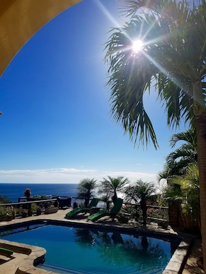 A clear blue sky, a swimming pool, and a view of the ocean.