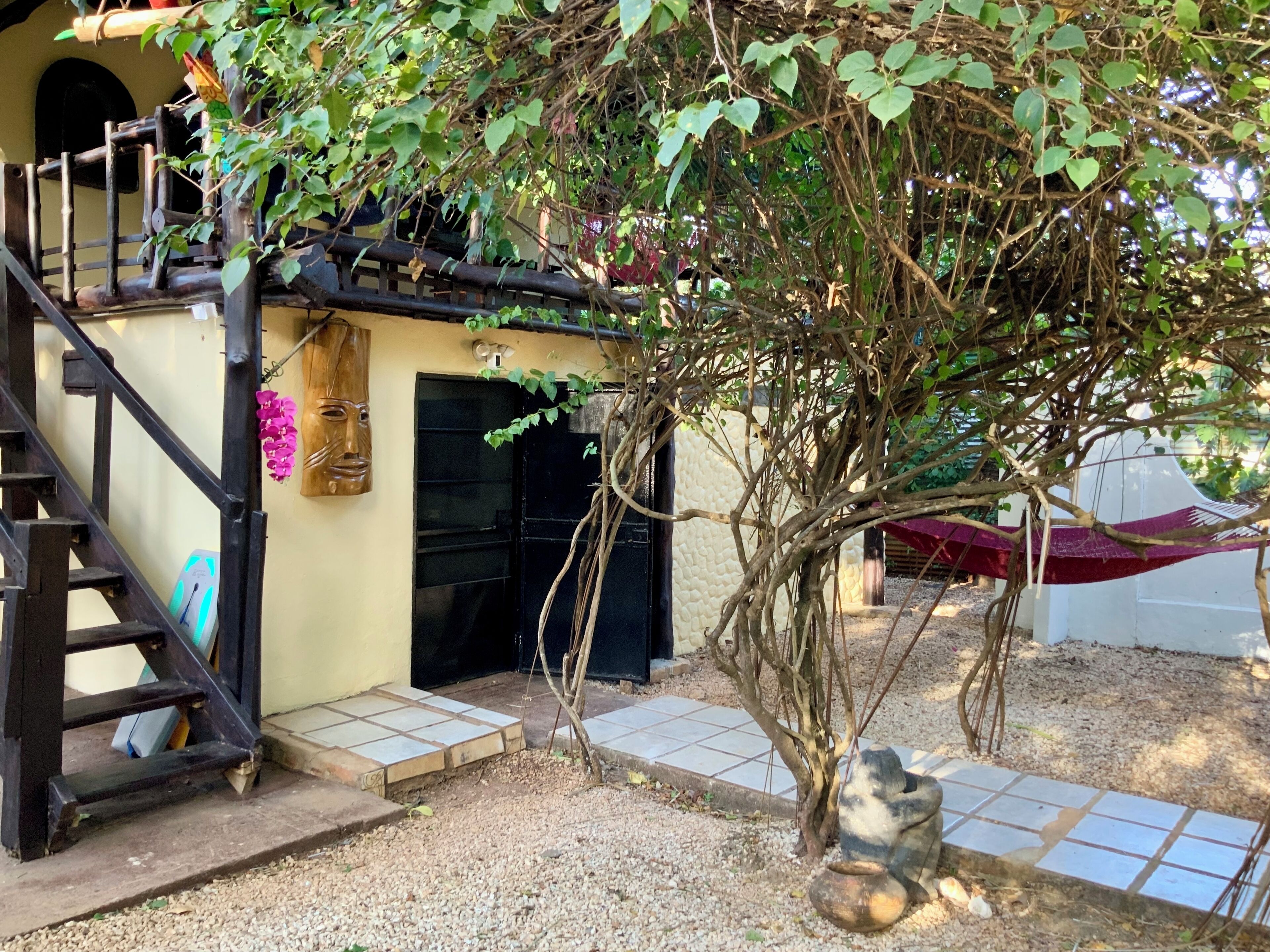 A rustic building with a wooden staircase, a black door, and a small porch area.