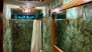 Une salle de bain avec des murs en pierre, un plafond en bois et un miroir.