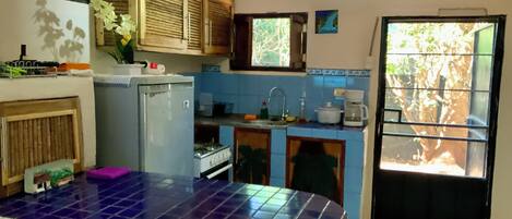 A kitchen with a blue tiled island, a refrigerator, a stove, and a sink.