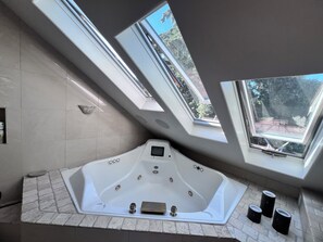 Een bad/douchecombinatie, een bubbelbad, een haardroger, handdoeken